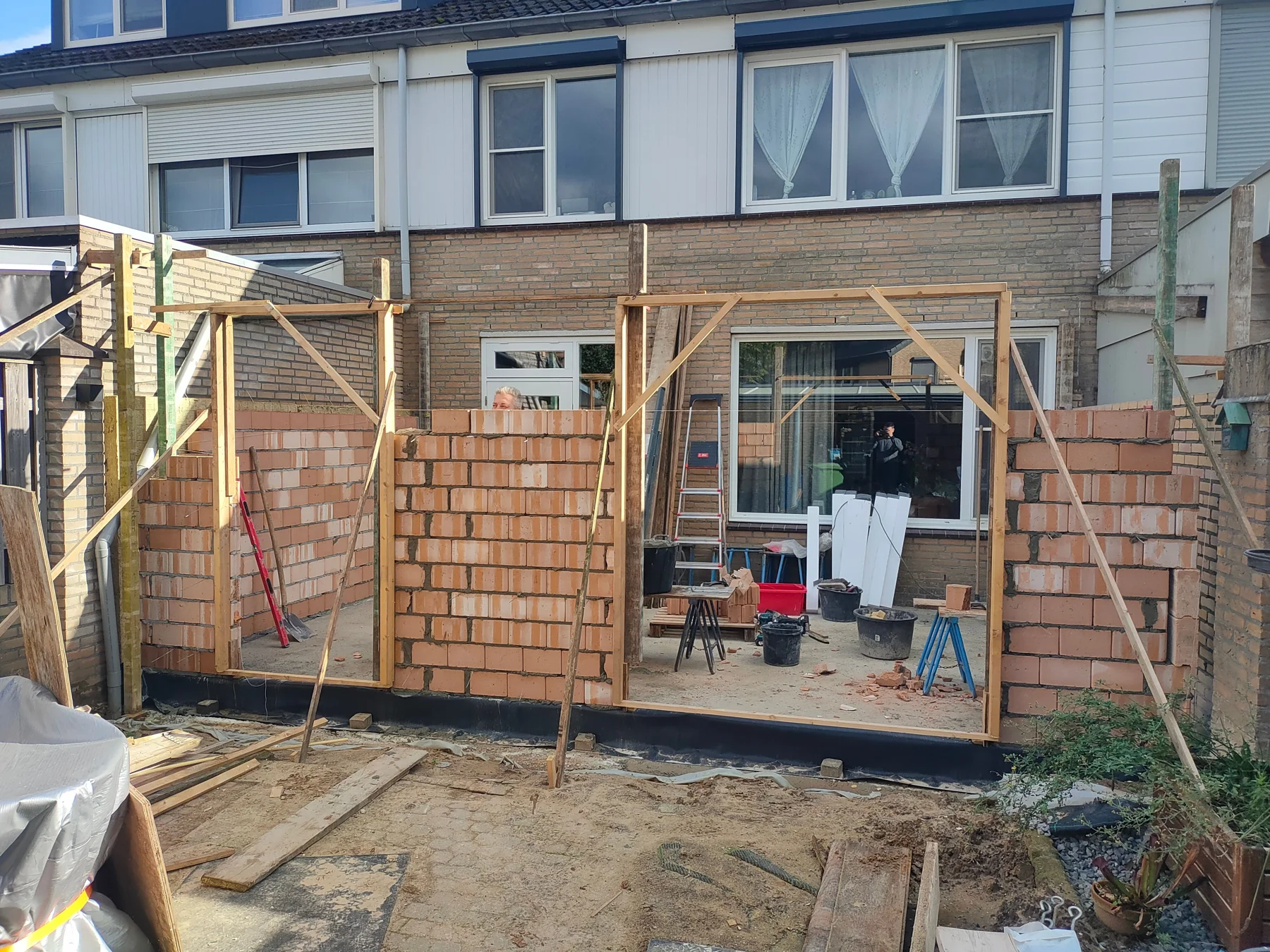Aanbouw in uitvoering met metselwerk en houten ondersteuning